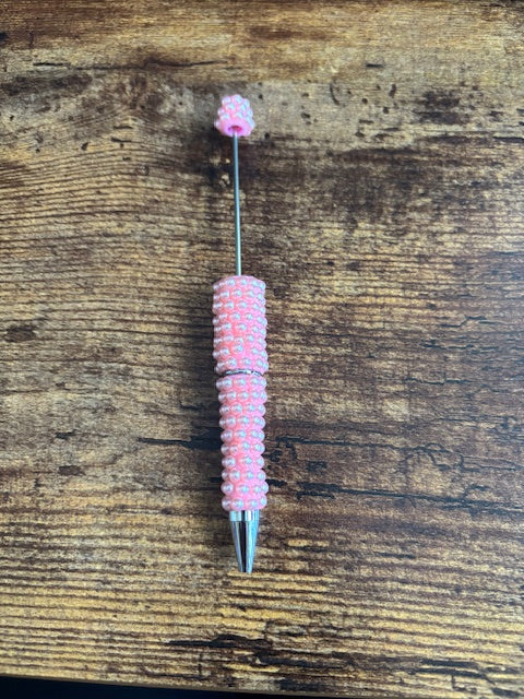 Pink beaded pen on a wooden surface