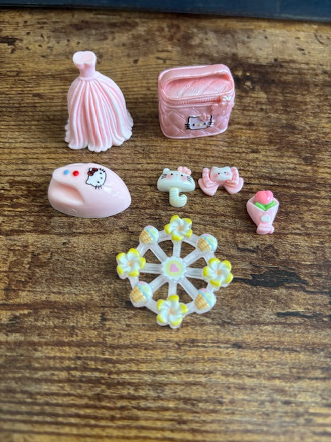 Decorative items including a small pink makeup pouch, a ferris wheel, and a flower bouquet on a wooden surface.