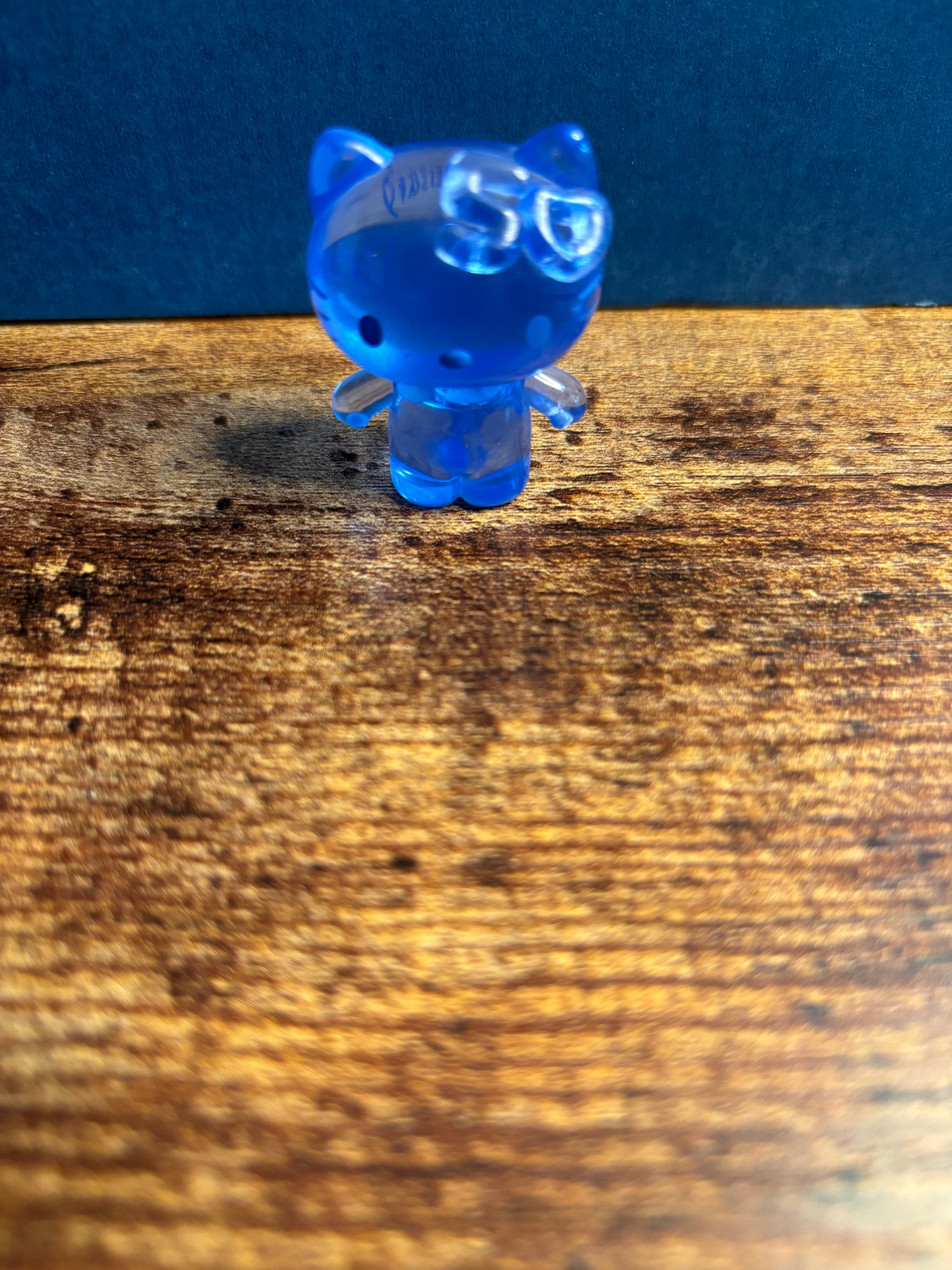 Blue transparent figurine on a wooden surface with a blue background