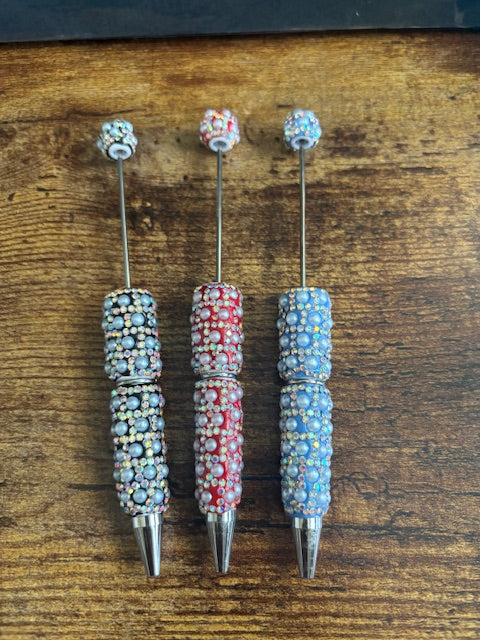 Set of decorative pens with pearl accents on a wooden surface