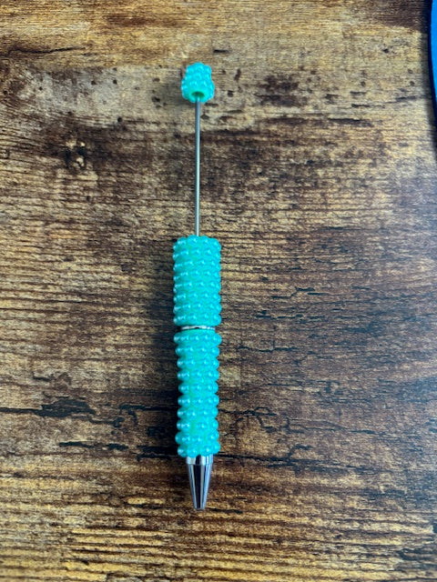 Turquoise textured pen on a wooden surface