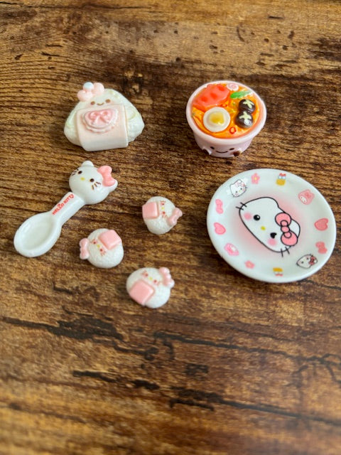 Set of small ceramic items including a bowl, spoon, and various decorative pieces on a wooden surface.
