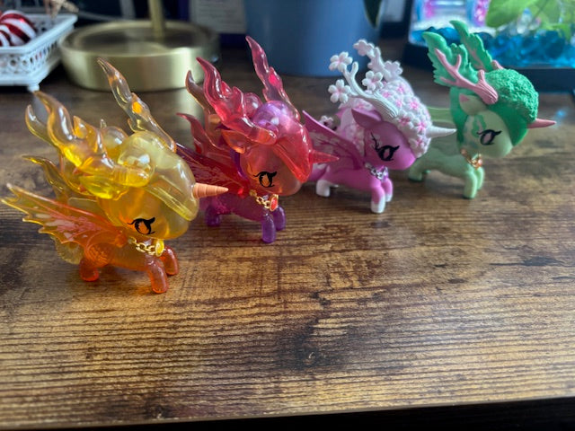 Four colorful dragon-like figurines on a wooden surface