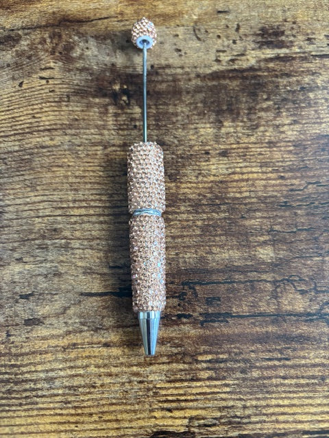 champagne rhinestone pen on wooden surface
