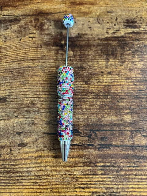 Decorative pen with multicolored beads on a wooden surface
