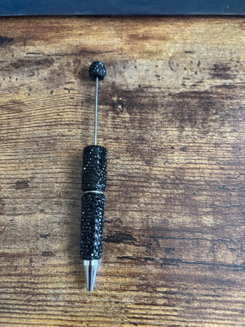 Black pen with glittery accents on a wooden surface