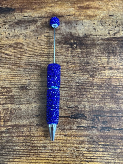 Blue pen with rhinestone accents on a wooden surface