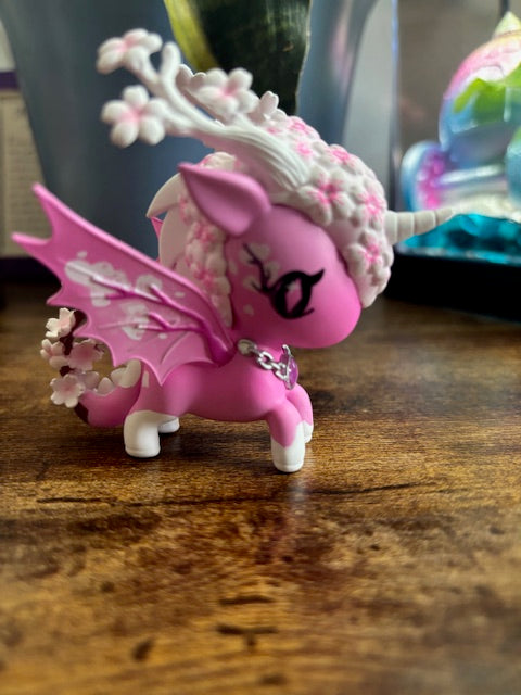 Pink and white cherry blossom dragon figurine on a wooden surface
