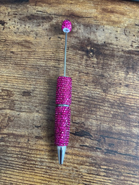 Pink glittery pen on a wooden surface