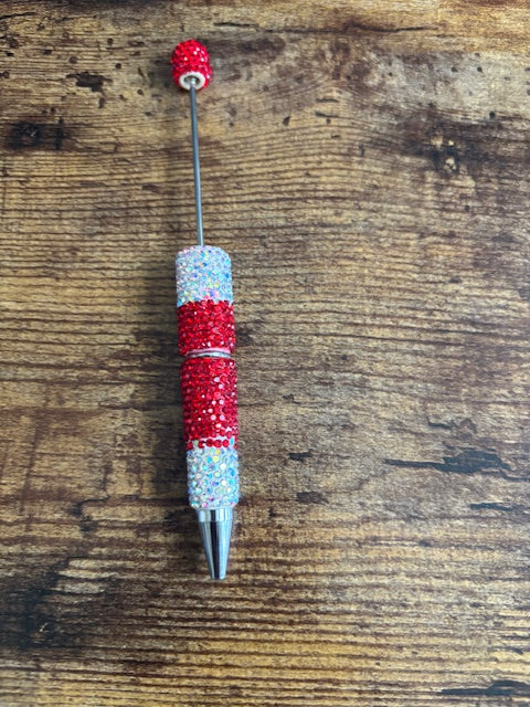 Decorative pen with red and silver accents on a wooden surface